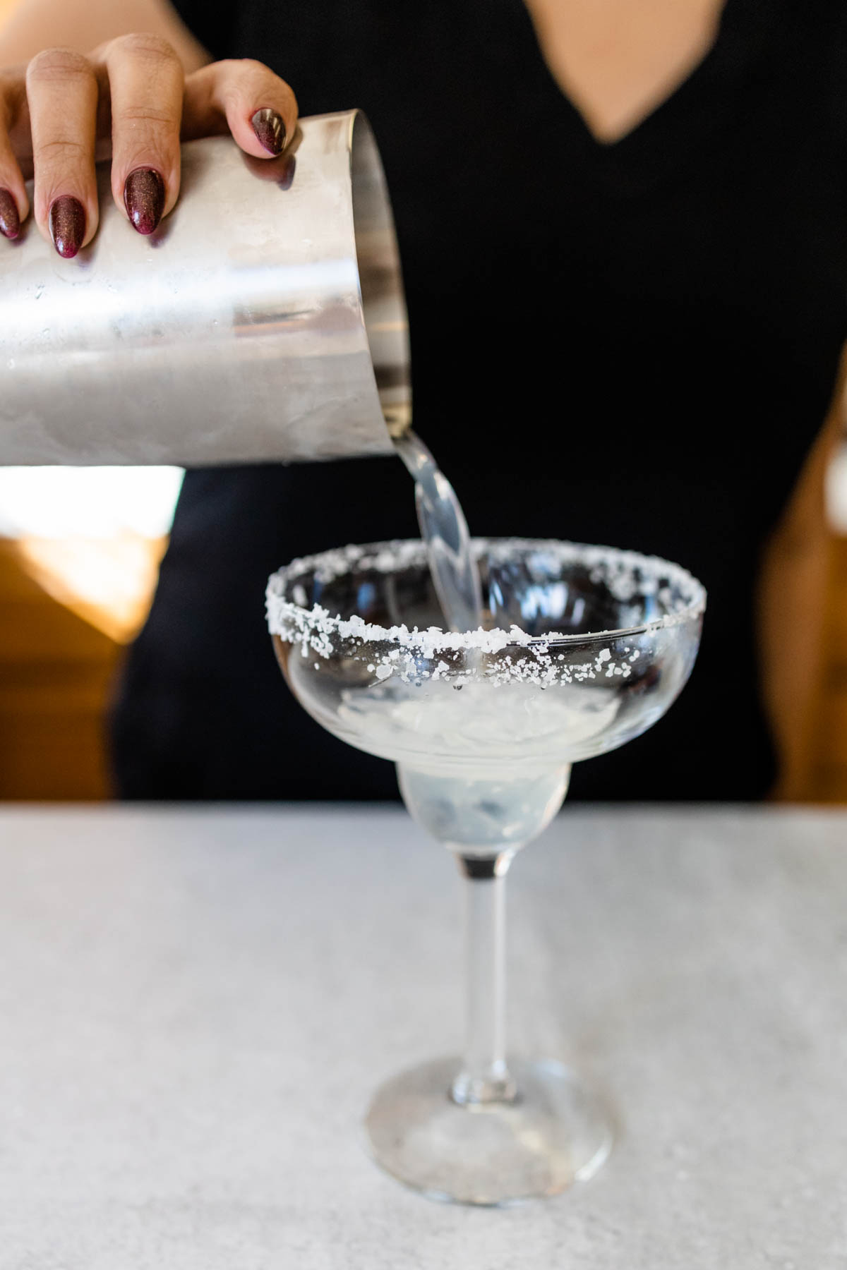Pouring a cocktail into a salt rimmed margarita glass.
