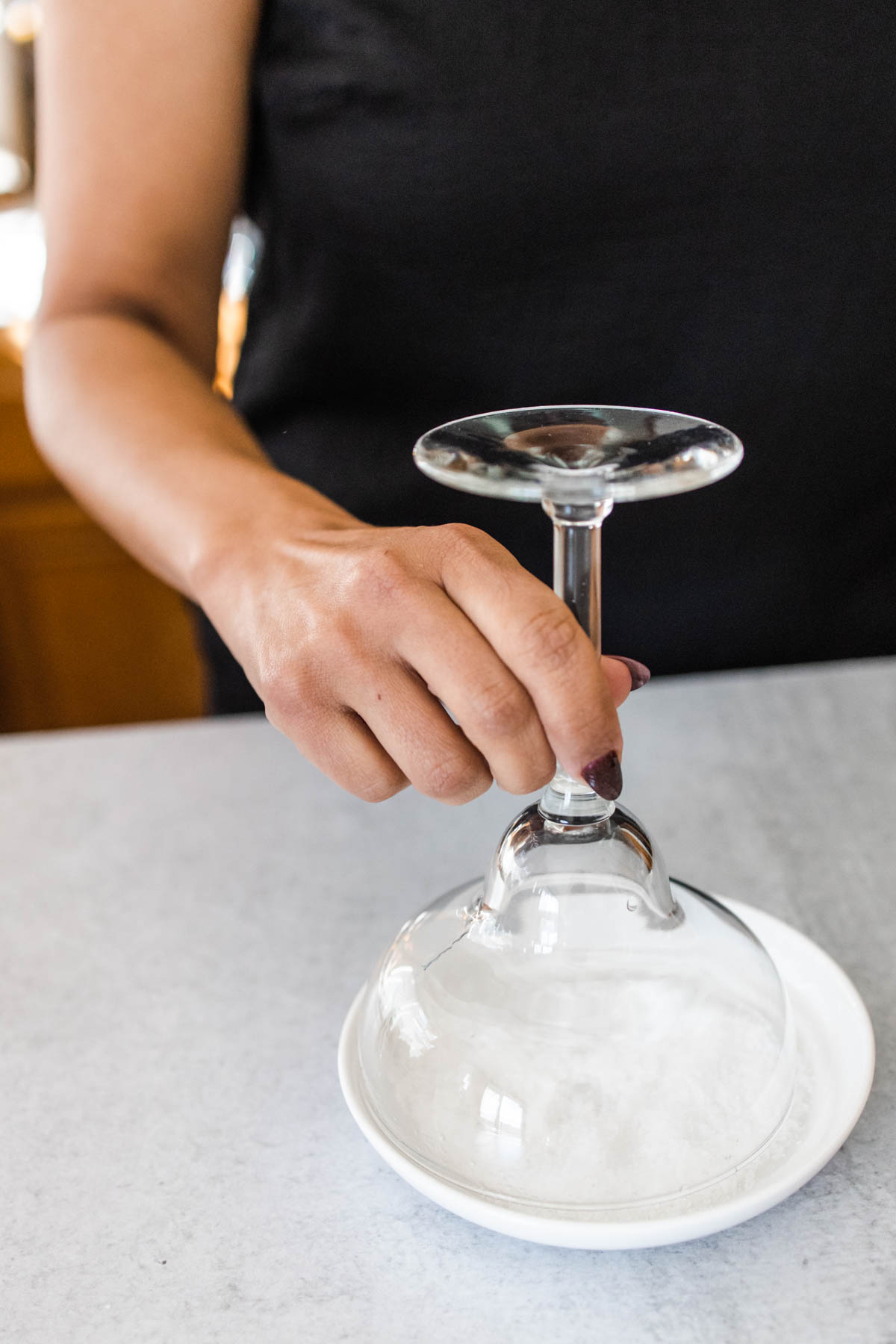 Dipping a margarita glass into a shallow plate of salt.