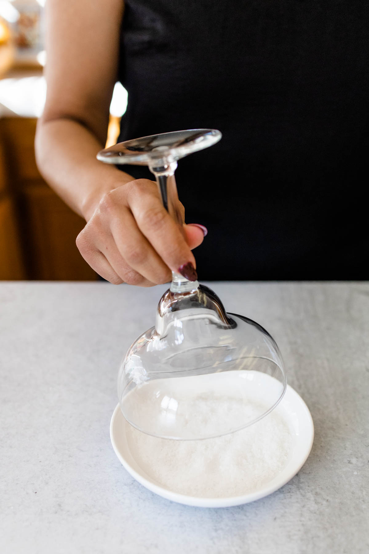 Woman adding salt to the rim of a margarita glass.