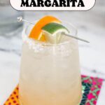 Text: The Best Skinny Margarita with a cocktail glass on a colorful napkin with a lime and orange wedge garnish.