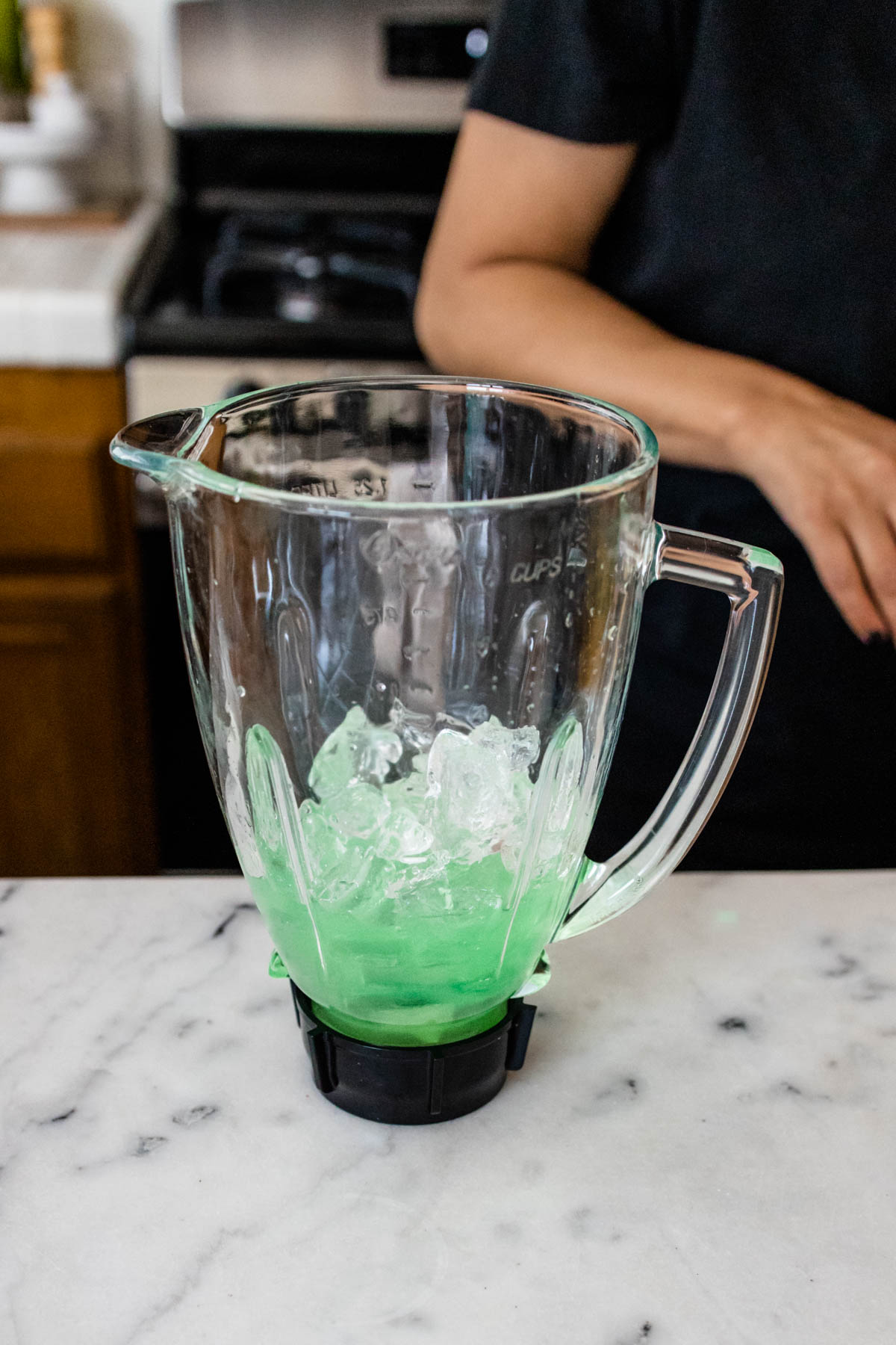 A blender holding a green liquid and ice.