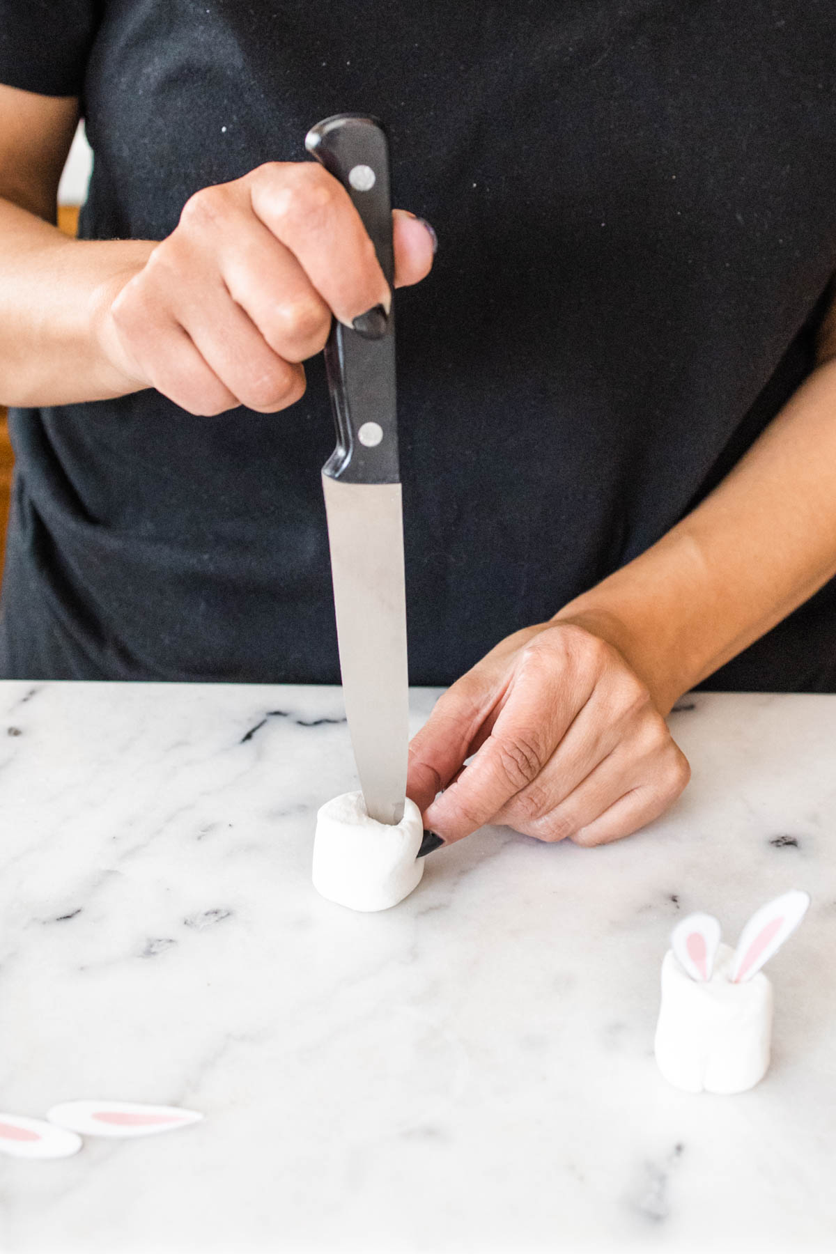 Woman using a knife to make a cut in a marshmallow for an Easter drink garnish.