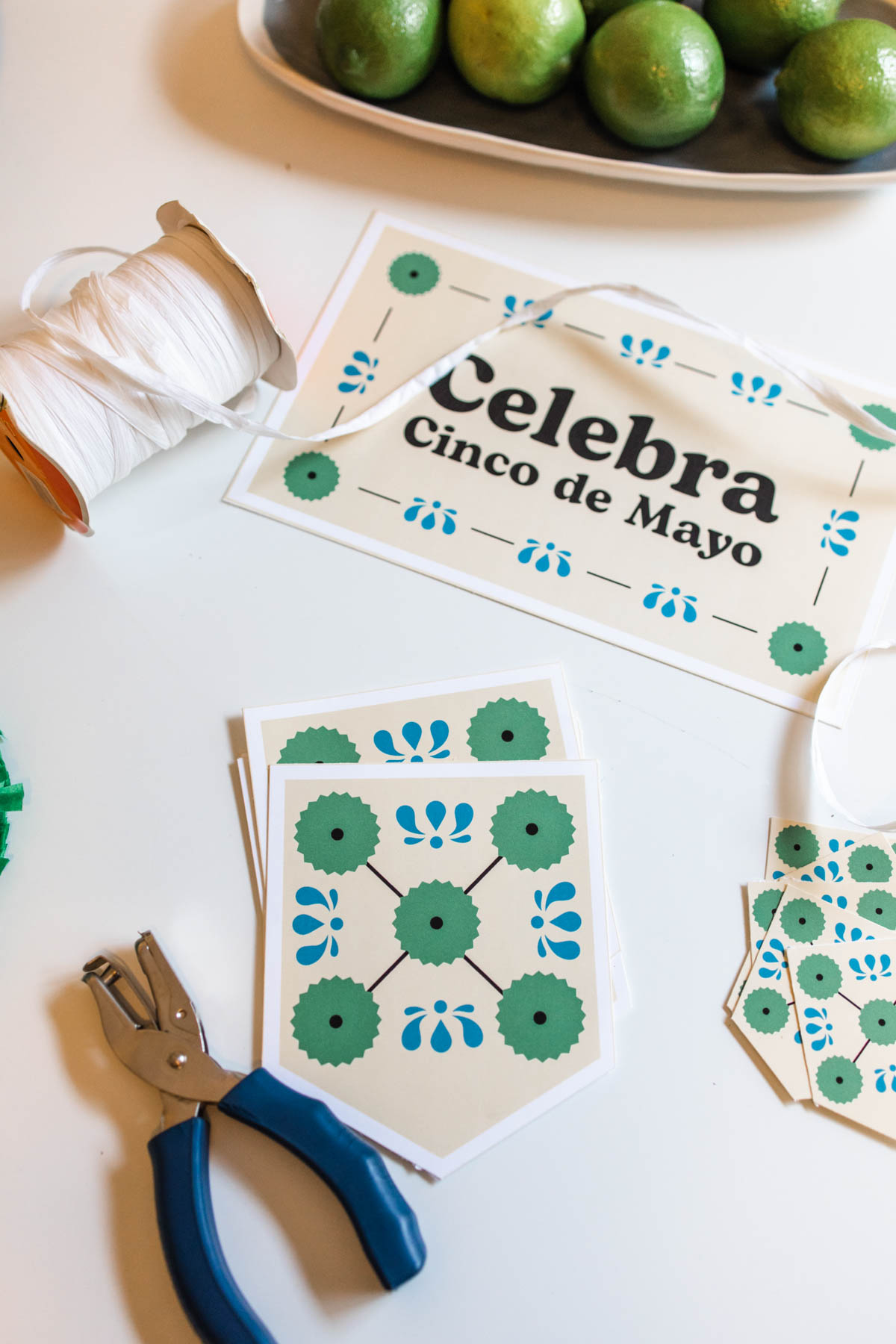 Printable party kit for Cinco de Mayo on a table next to a hole punch and white ribbon.