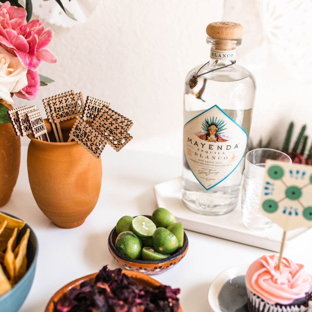 A party table with a bottle of tequila on a white tray for Cinco de Mayo.