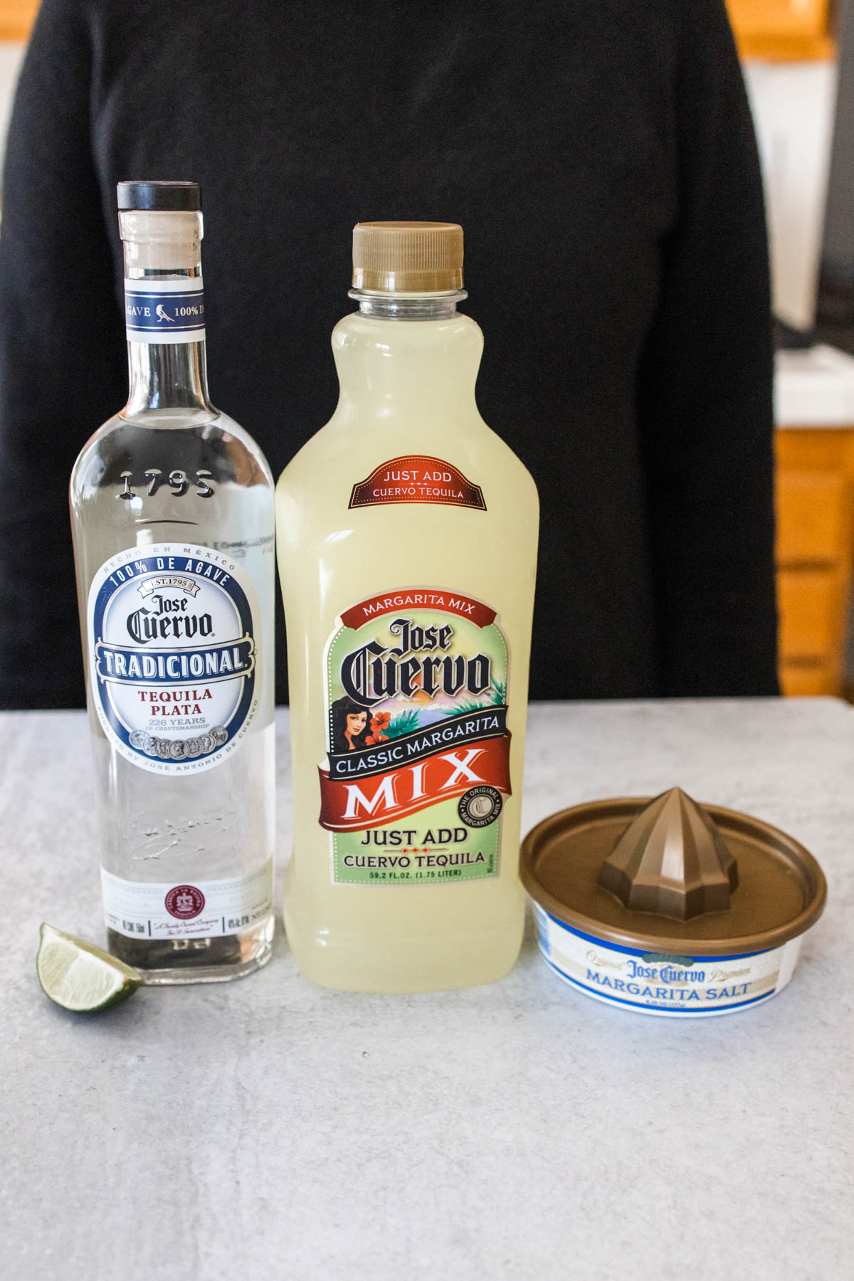 Jose Cuervo Tradicional tequila with Jose Cuervo margarita mix, a fresh slice of lime and margarita salt on a counter.