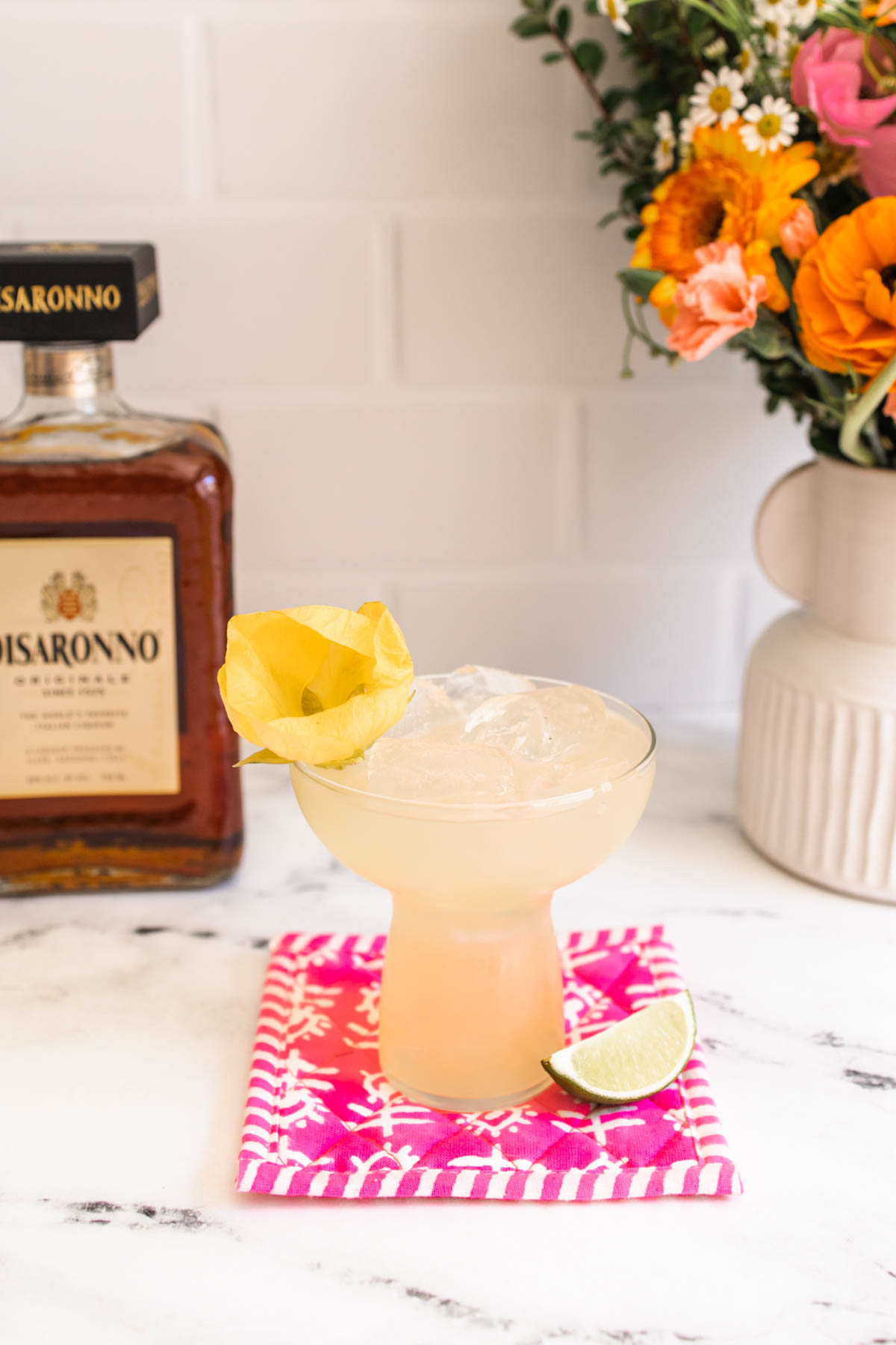 A glass of delicious Italian margarita garnished with a yellow flower.