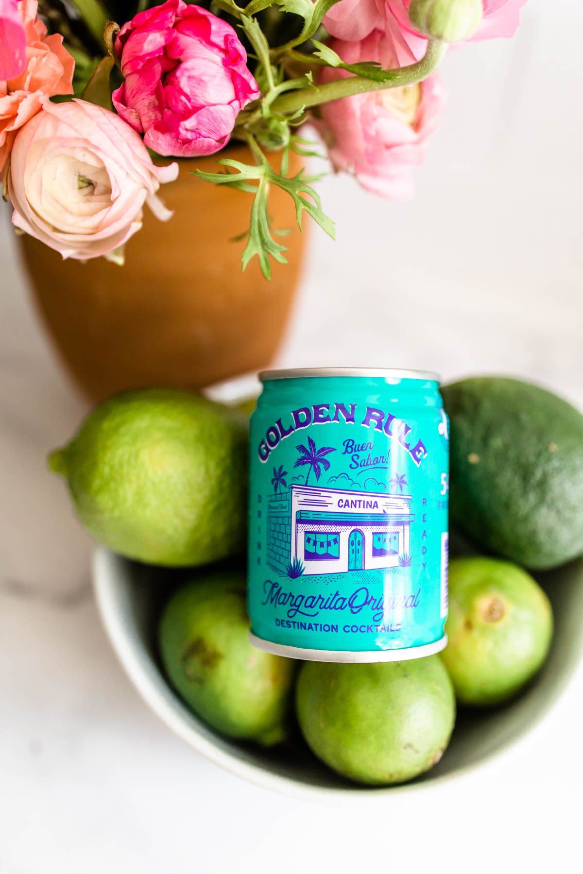 A can of Golden Rule Margarita Original nestled on a bowl of fresh limes. 