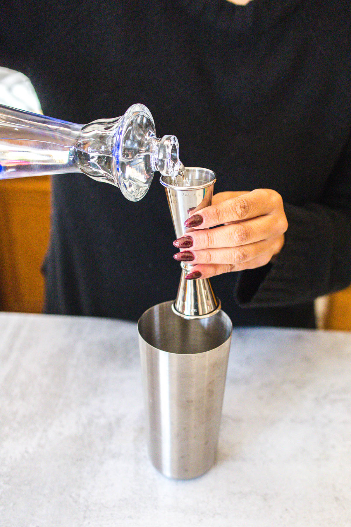A woman's hand pouring some Clase Azul tequila into a jigger.