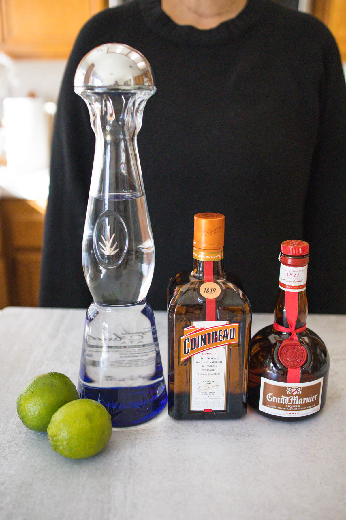 Ingredients of a cadillac margarita including fresh lime, Clase Azul tequila, Cointreau, and Grand Marnier.
