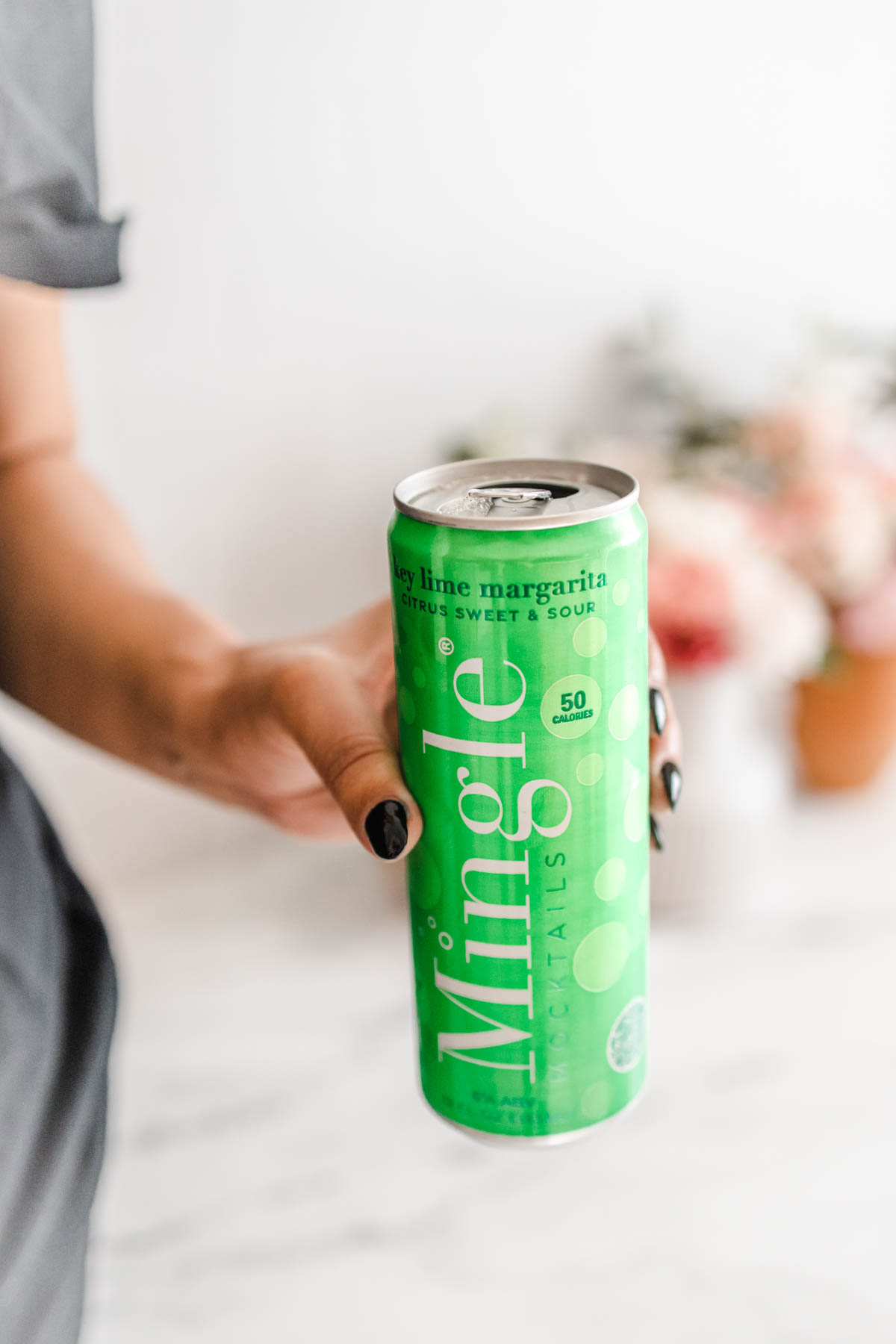 A hand holding a single can of Mingle Mocktails Key Lime Margarita.