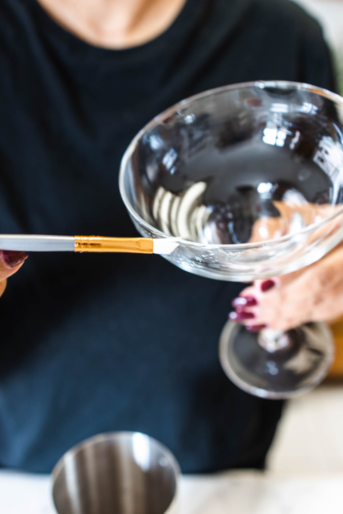 Moistening a portion of the margarita glass using a brush.