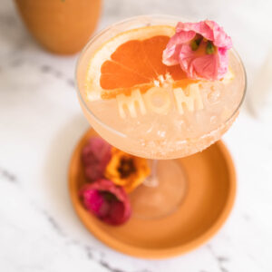 Beautiful rosé margarita perfect for mother's day with "mom" ice garnish and edible pink flower on top.