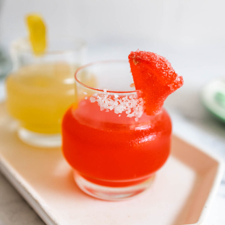 A vibrantly red Deadpool cocktail inside a hexagon plate in front of a yellow Wolverine margarita.