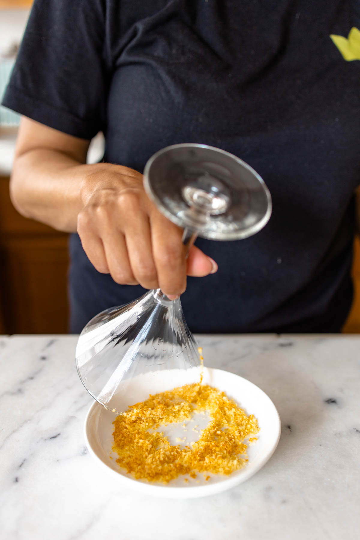 A person dipping a glass into a plate with orange salt.