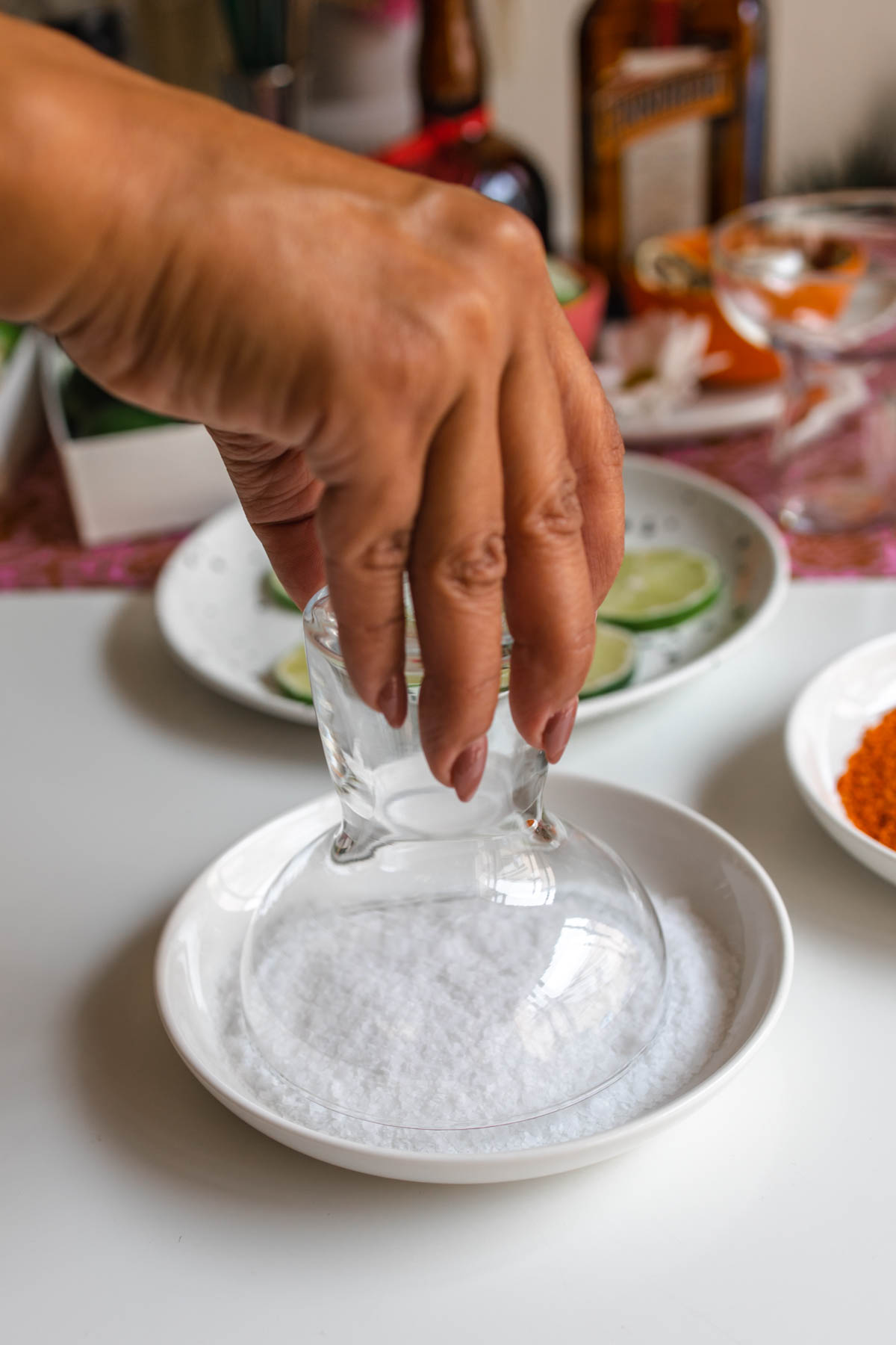 A person dipping a margarita glass into a plate with salt.
