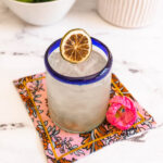 A glass of Seedlip margarita with ice and dehydrated lime wheel on top.