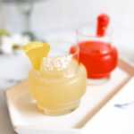 A yellow Wolverine margarita inside a salted rim glass and garnished with candied lemon slice.