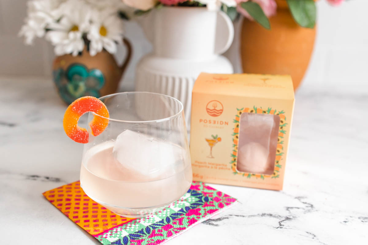 Poseidn Peach Margarita Cocktail Bombs box alongside a glass of peach margarita.