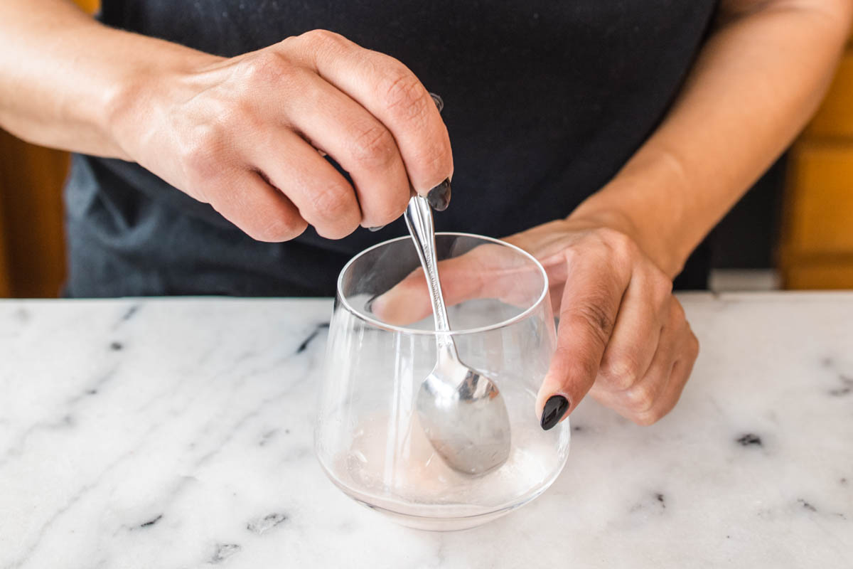 A person stirring a peach margarita mix with a spoon.