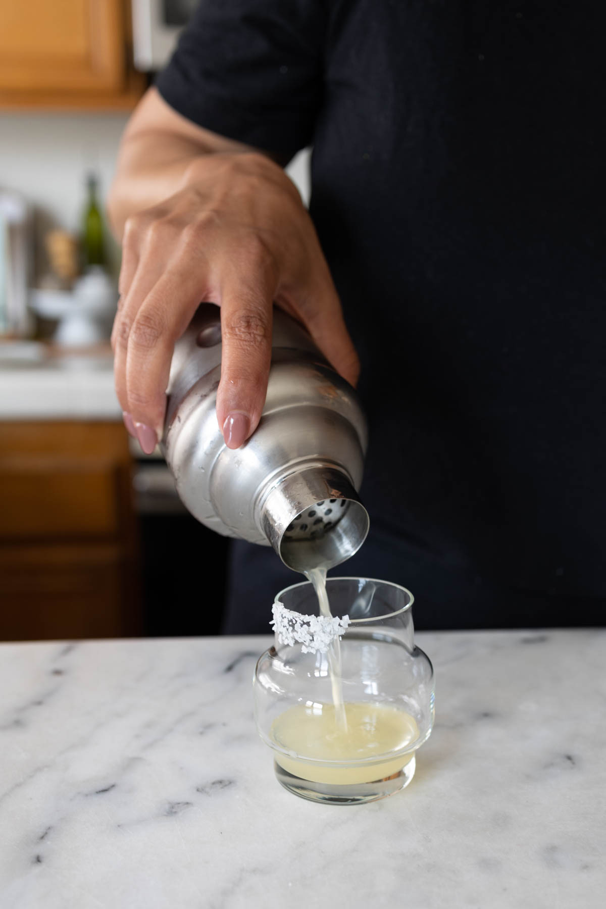 A person pouring Wolverine Margarita into a small salted-rim glass.