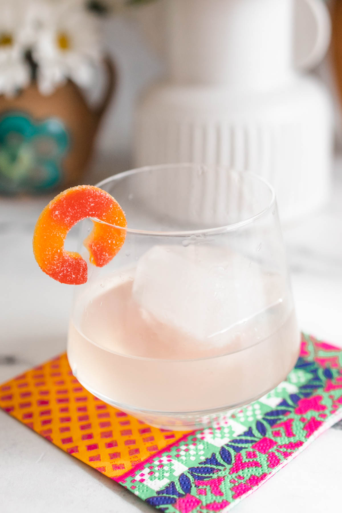 A close-up shot of a peach margarita made using Poseidn Peach Margarita Cocktail Bombs with a sour candy garnish.