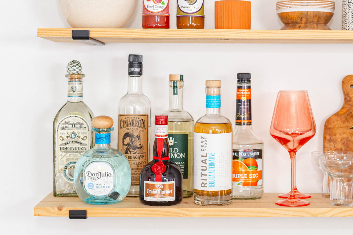 Bottles or tequila and Triple Sec on a wall shelf.